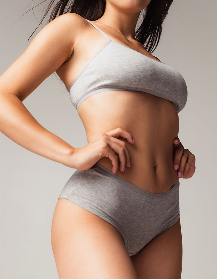 Woman touching her waist and wearing gray sports bra and boy shorts